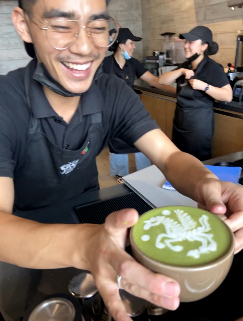Barista showing off a foamy matcha latte.