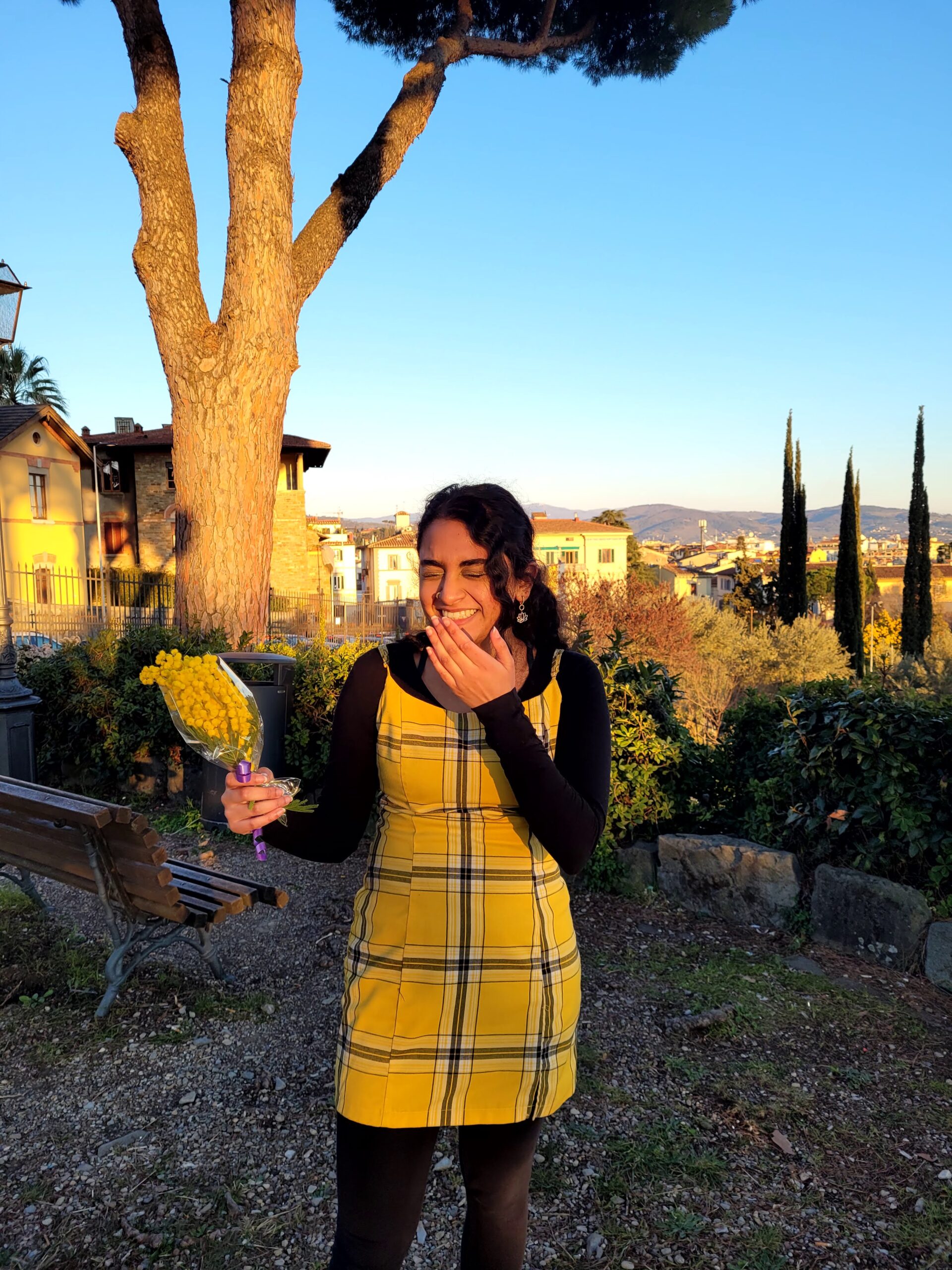 Eshika smiling at a yellow flower
