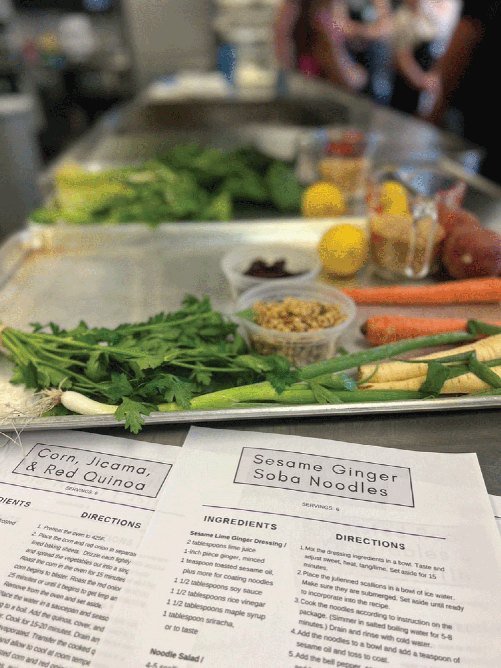 A tray of vegetables next to a paper recipe for sesame ginger soba noodles.