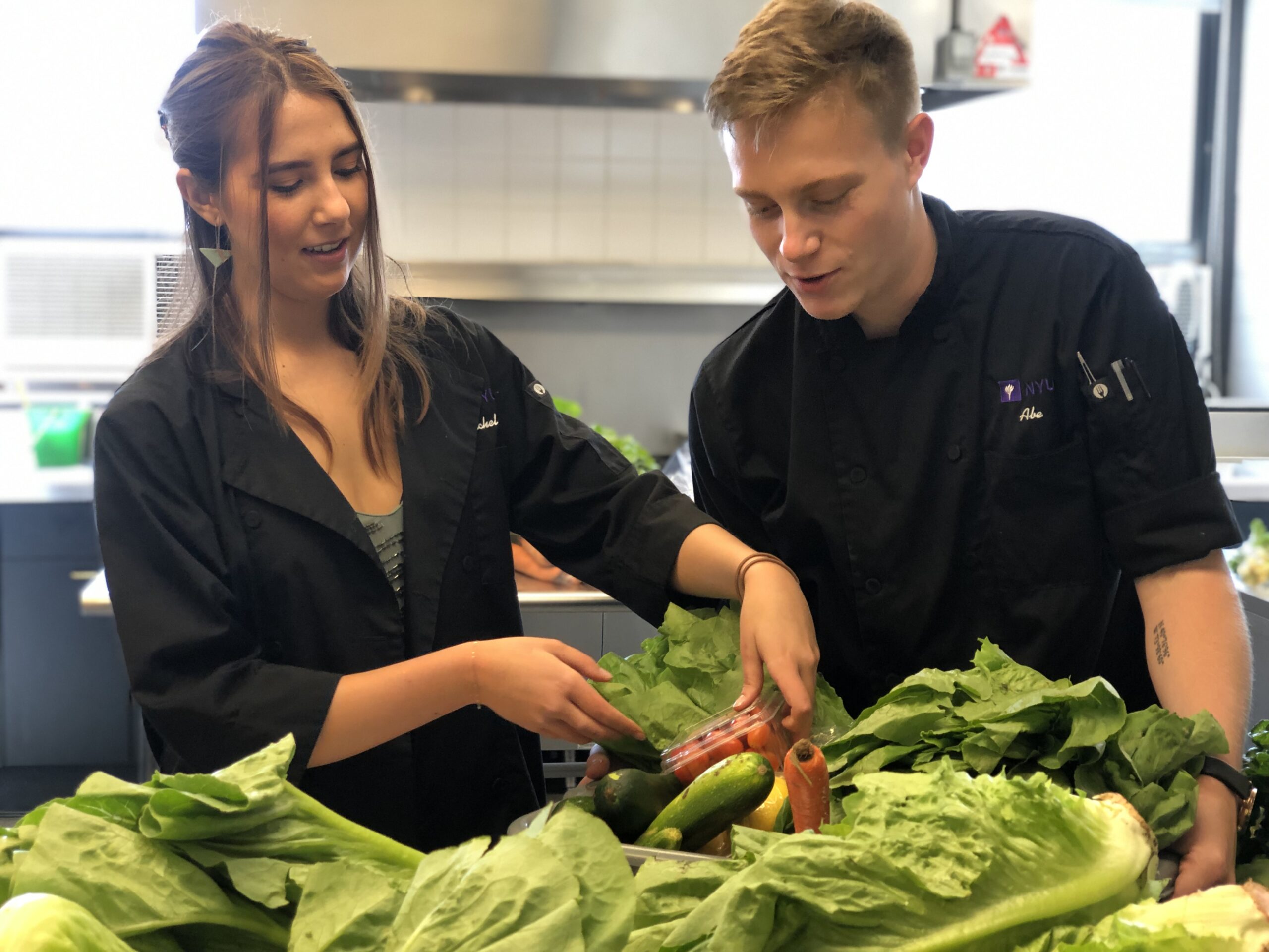 Two students unpacking a container of fresh vegetables in the Food Lab.