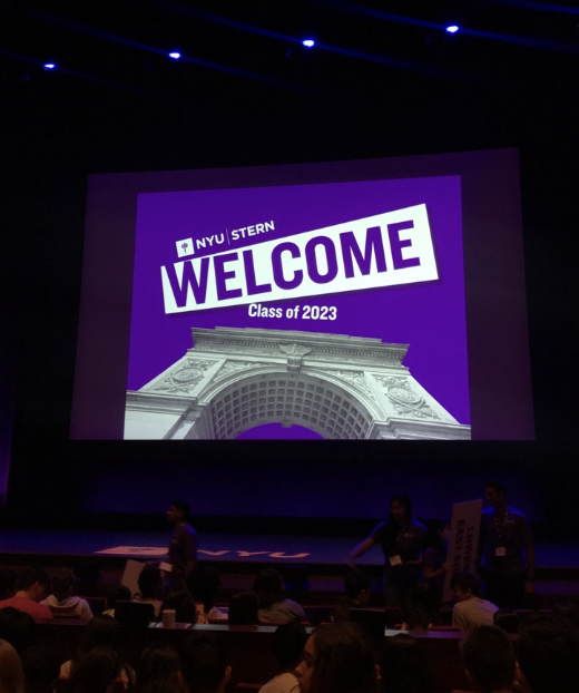 An auditorium view of a projection screen with Welcome on a purple background.