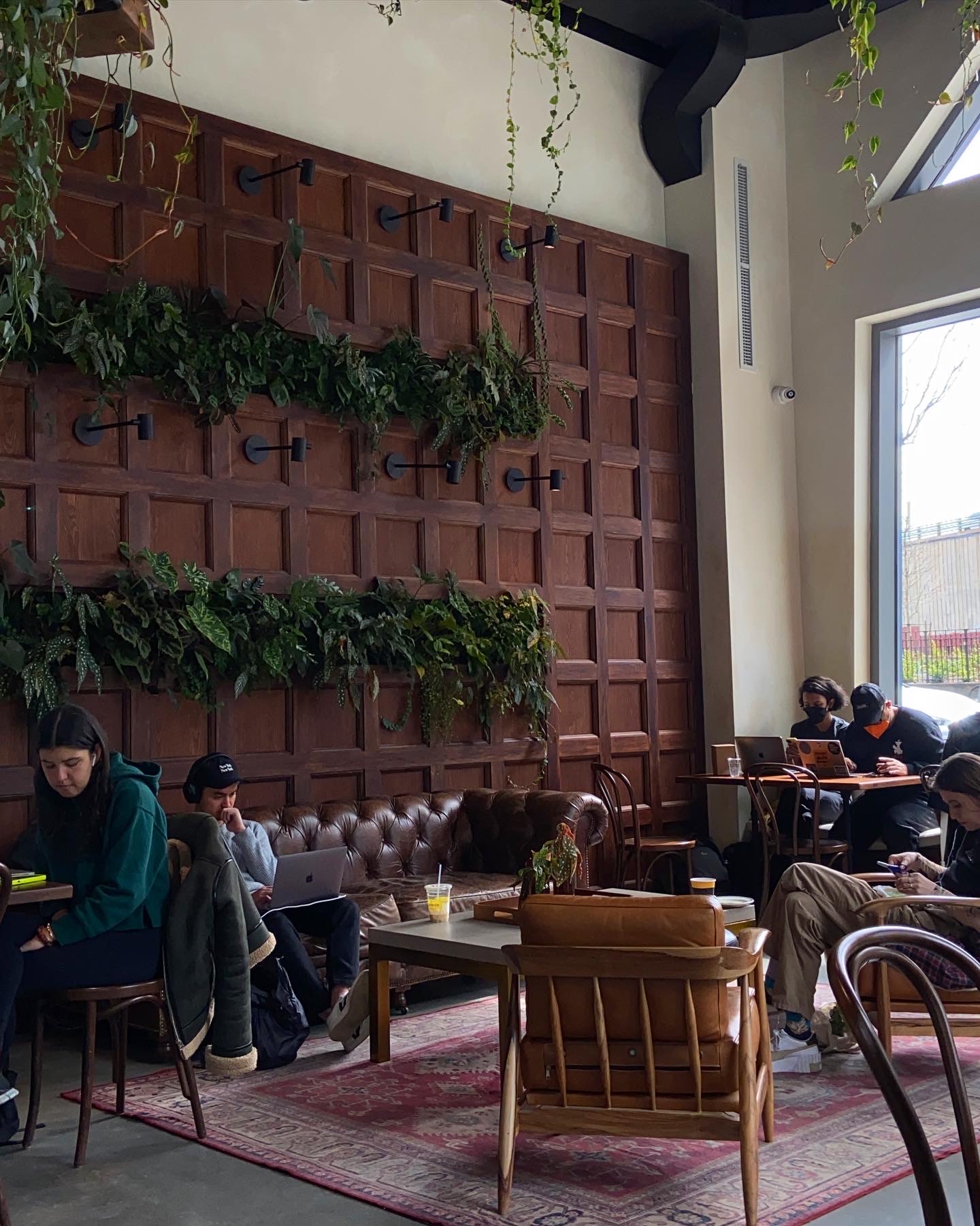 a plant-filled coffee shop in Dumbo with tables and couch seating