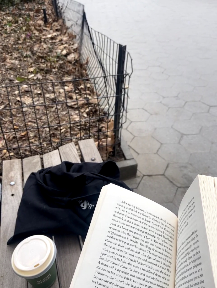 a book and coffee on a park bench in Madison Square park