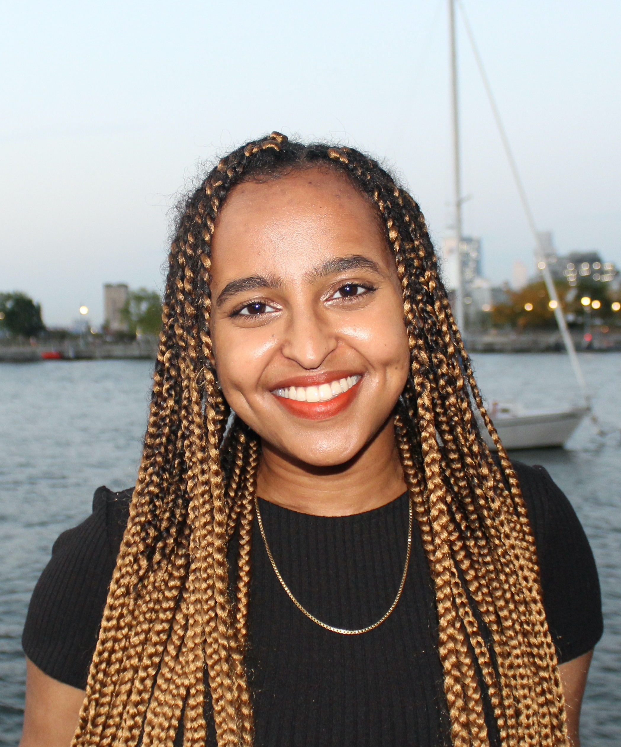 Hanna Gebremichael, an NYU student of color, in front of a lake with a sailboat.