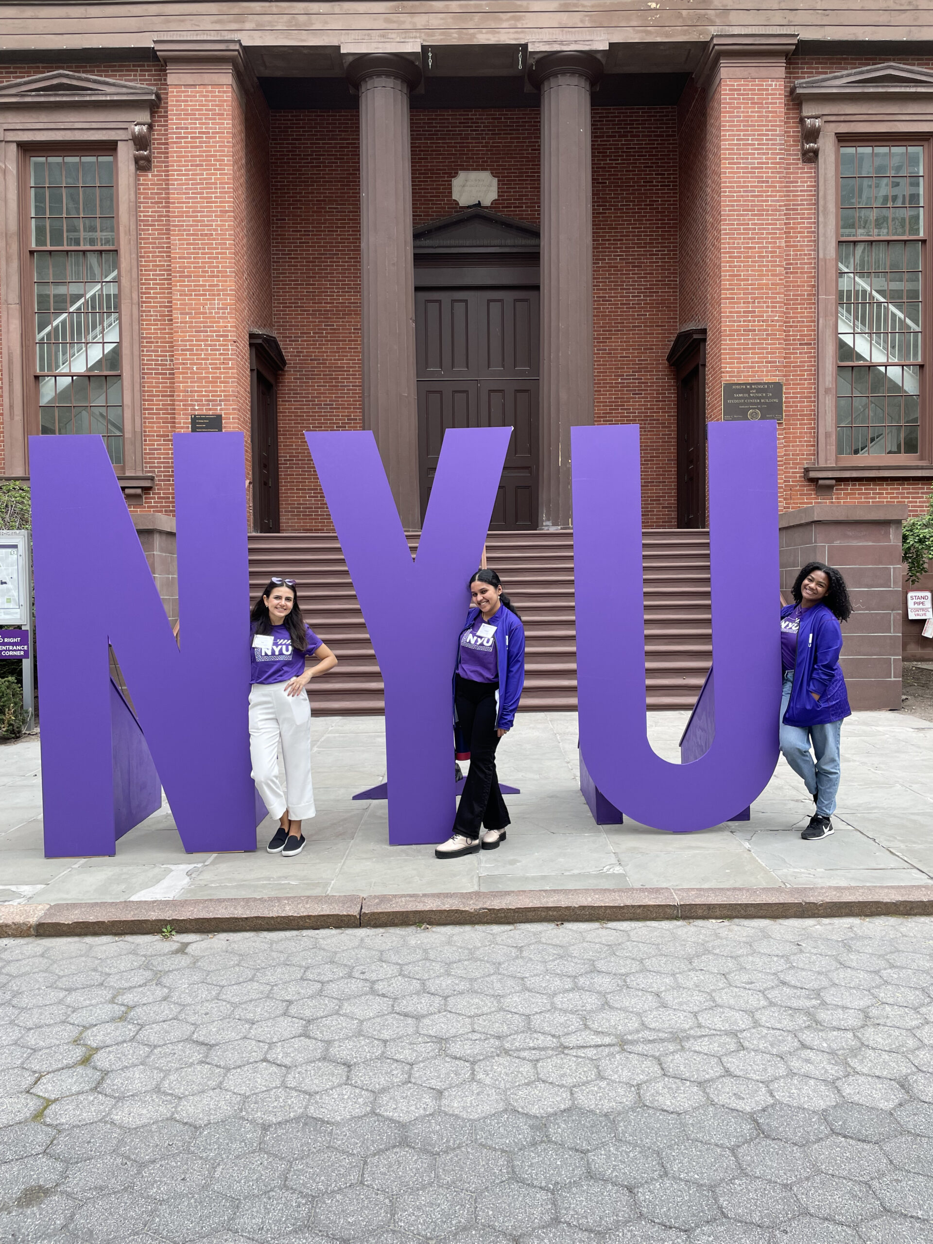 Anjana and fellow ambassadors pose with an NYU sign wearing purple gear.