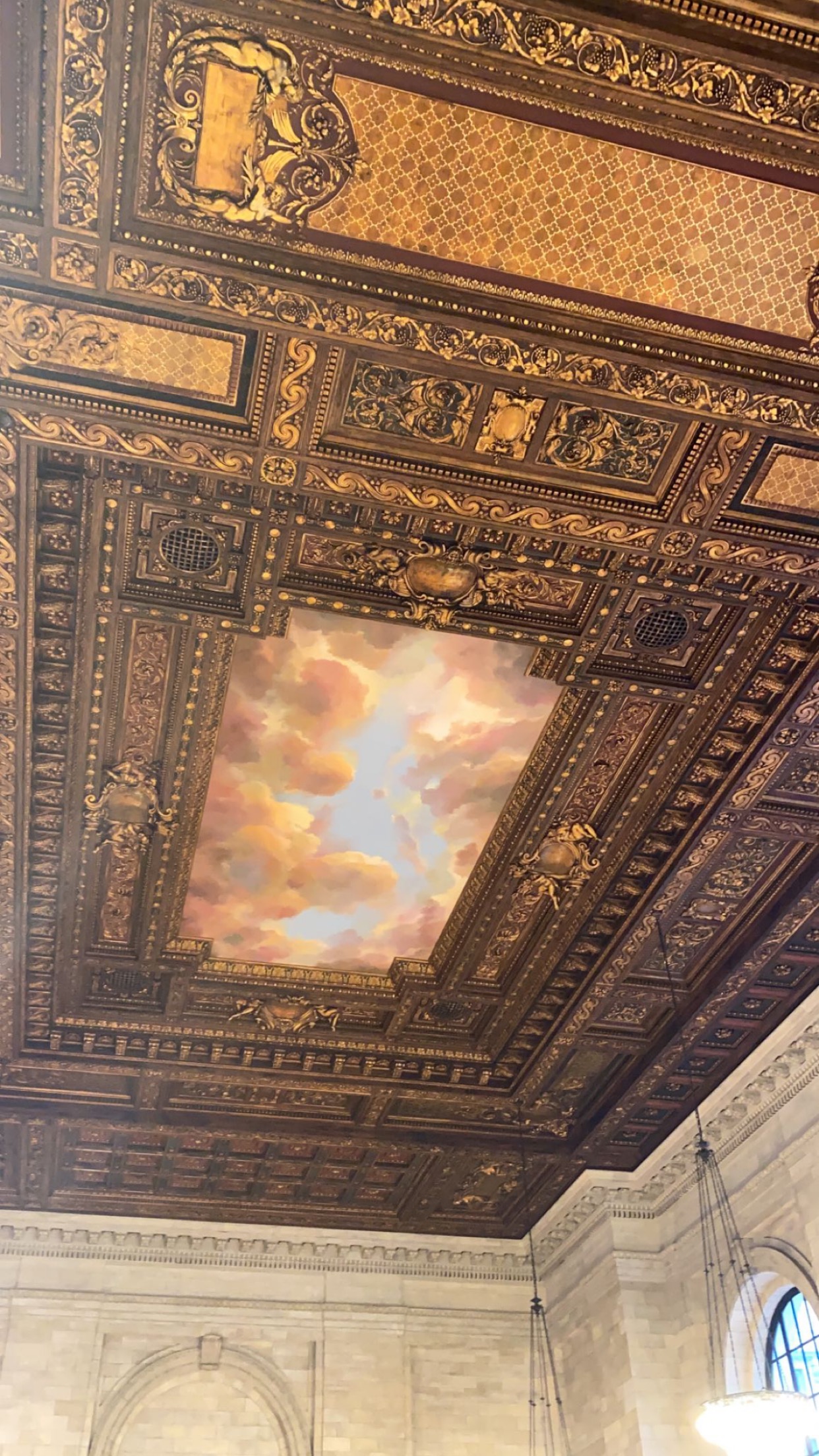 An elaborate gold ceiling with clouds painted on it.