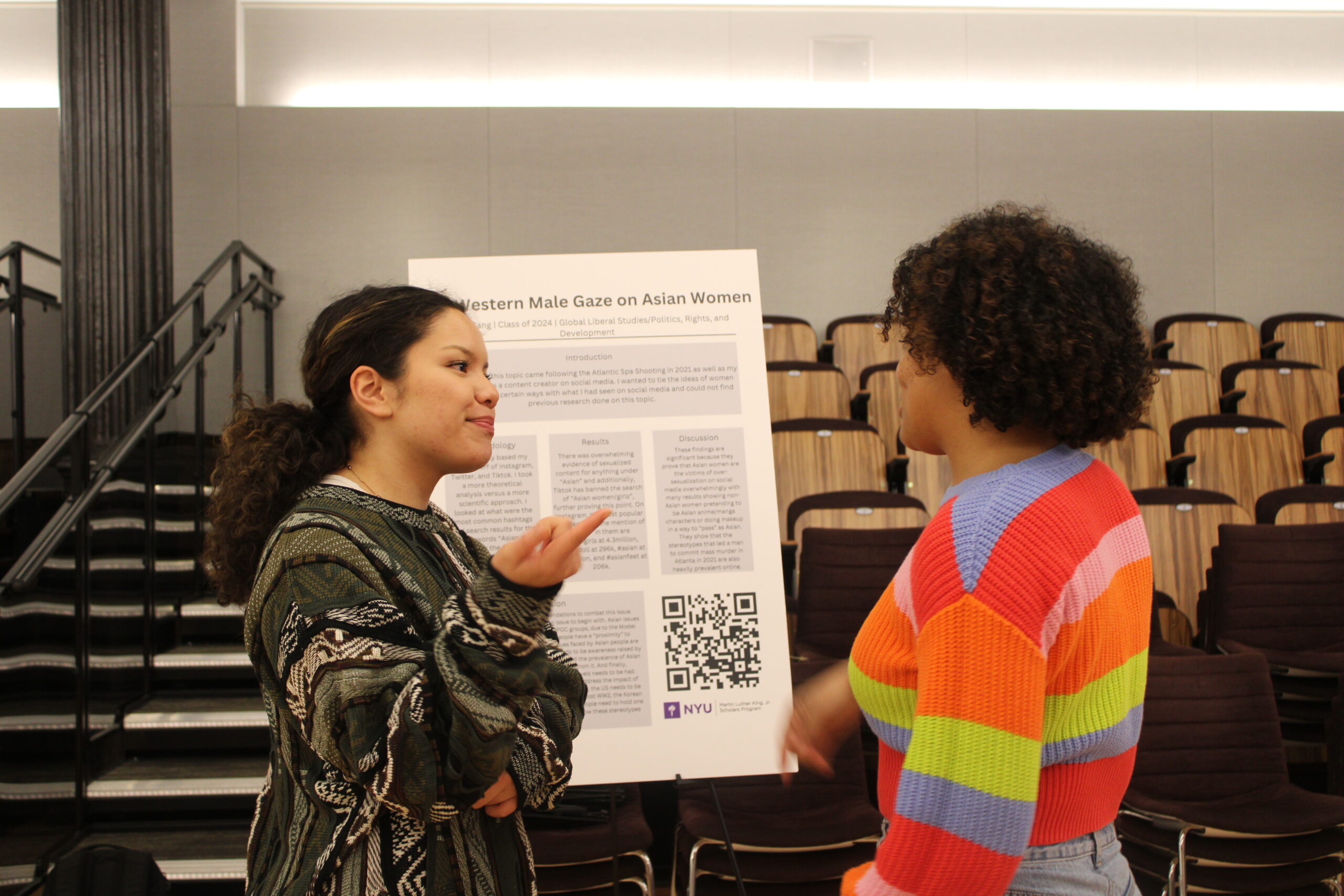 Two scholars speaking in front of a poster board