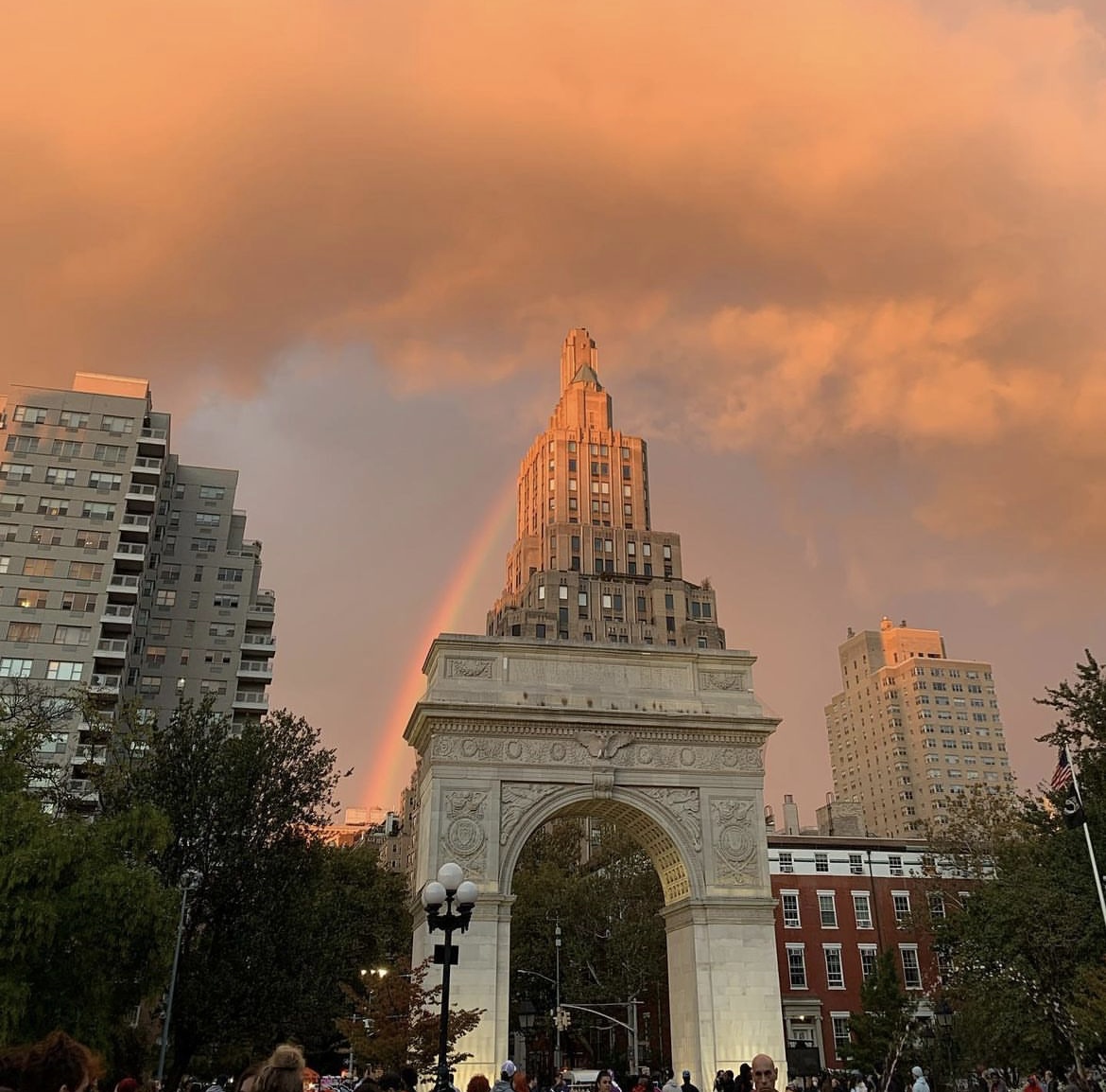 As the sun is setting, there is a rainbow over the Washington Square Arch in New York City.