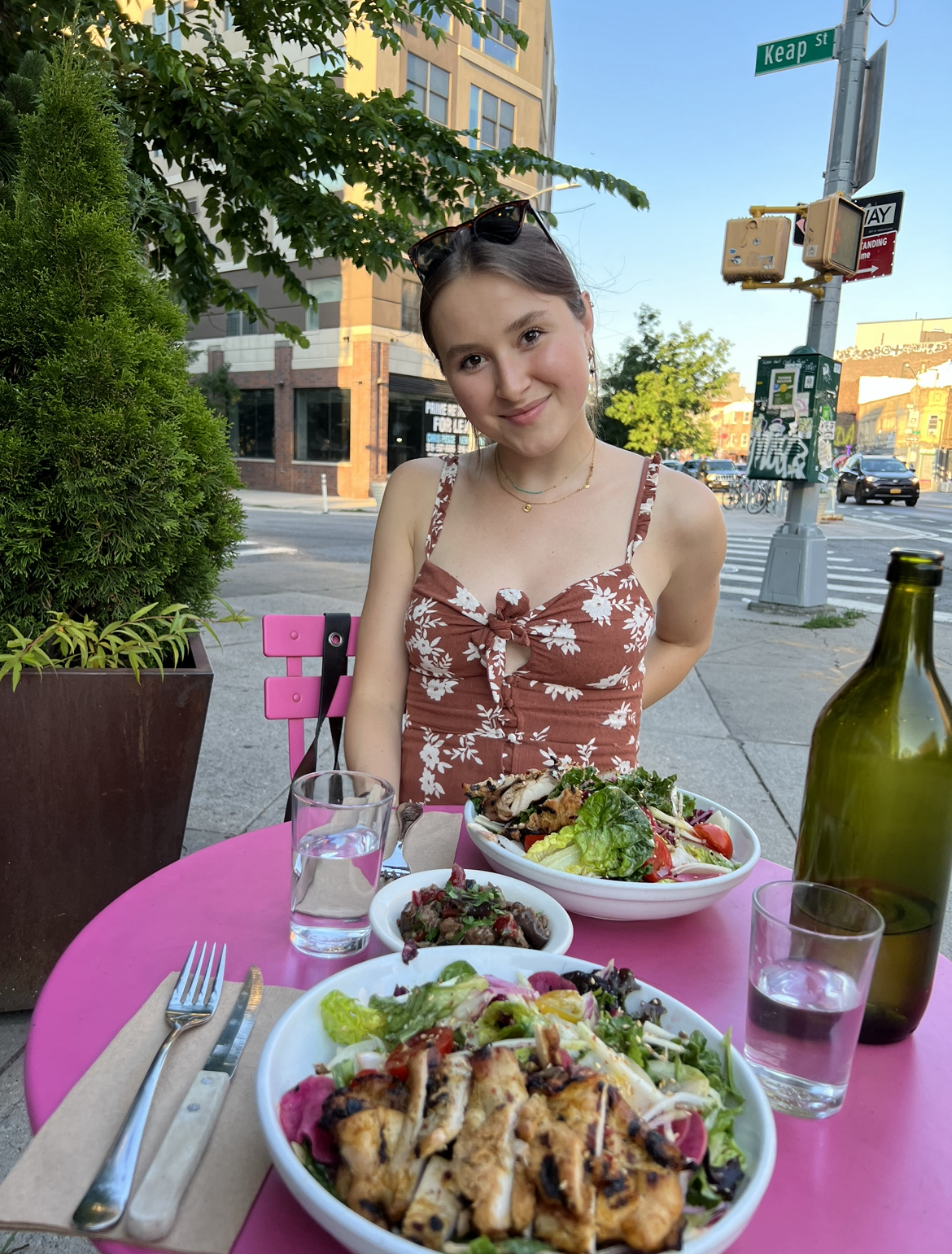 The author and a salad with grilled chicken sitting outside a restaurant in New York City during the summer.