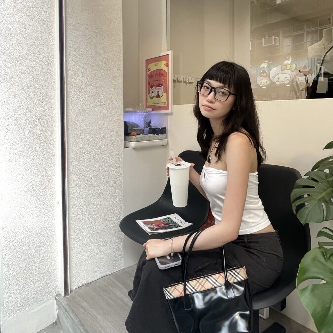 A student of color sits on a chair holding a cup of boba tea.