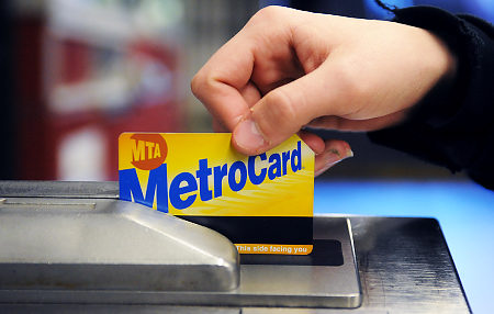 A hand swiping a MetroCard at a turnstile.