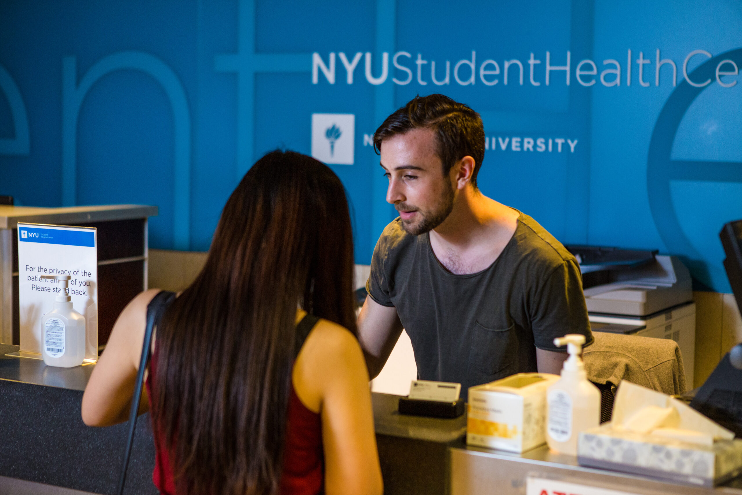 A student receptionist helping a visitor at the NYU Student Health Center.