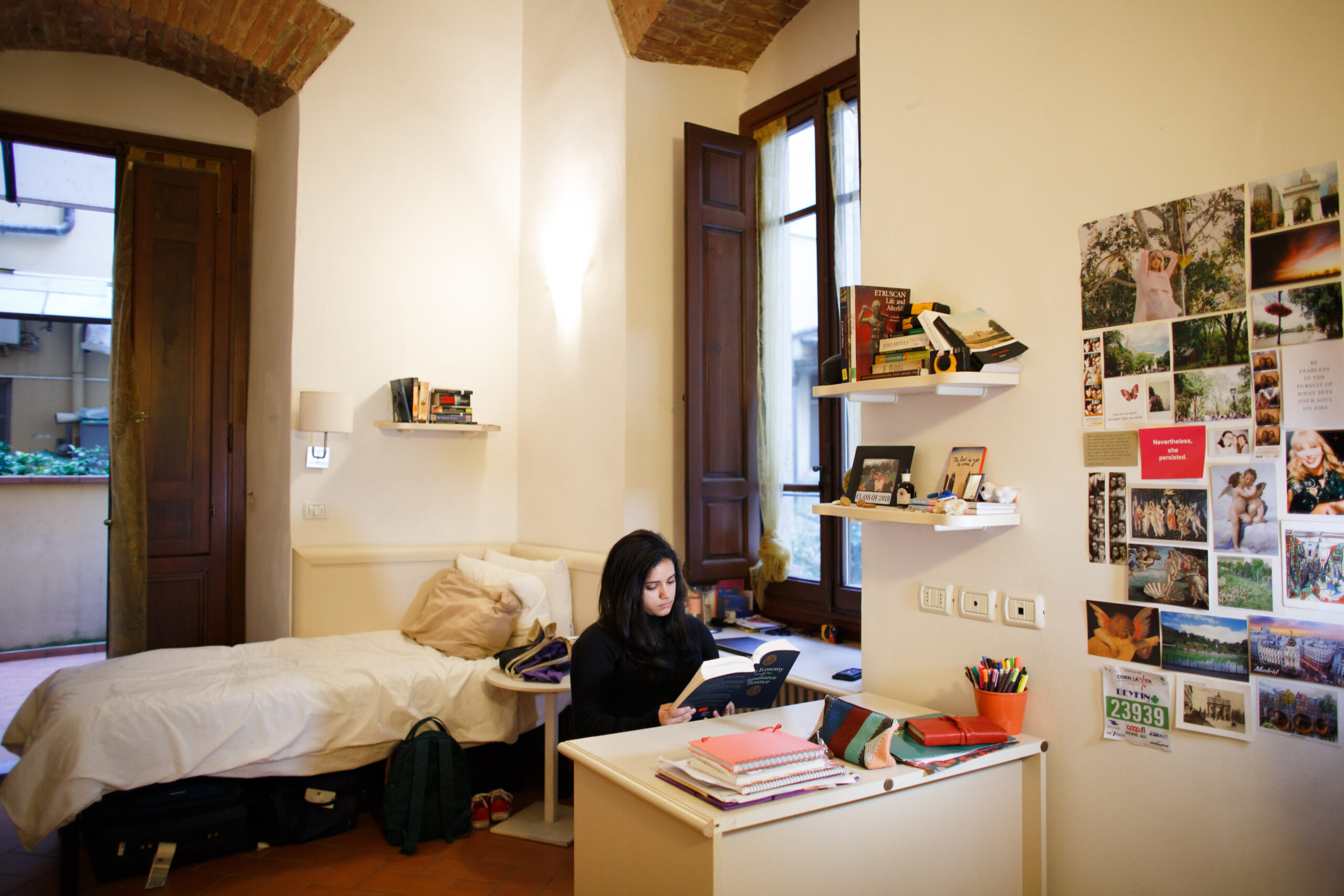A student reading a book in their dorm room in Florence.