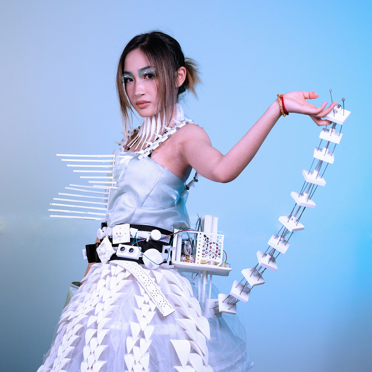 A model standing in white gown fashioned with electronics.