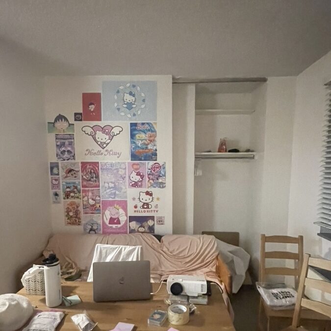a dorm room decorated with posters and desk objects