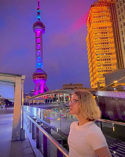 Sarah in front of the Oriental Pear Tower in Shanghai, China, at night.