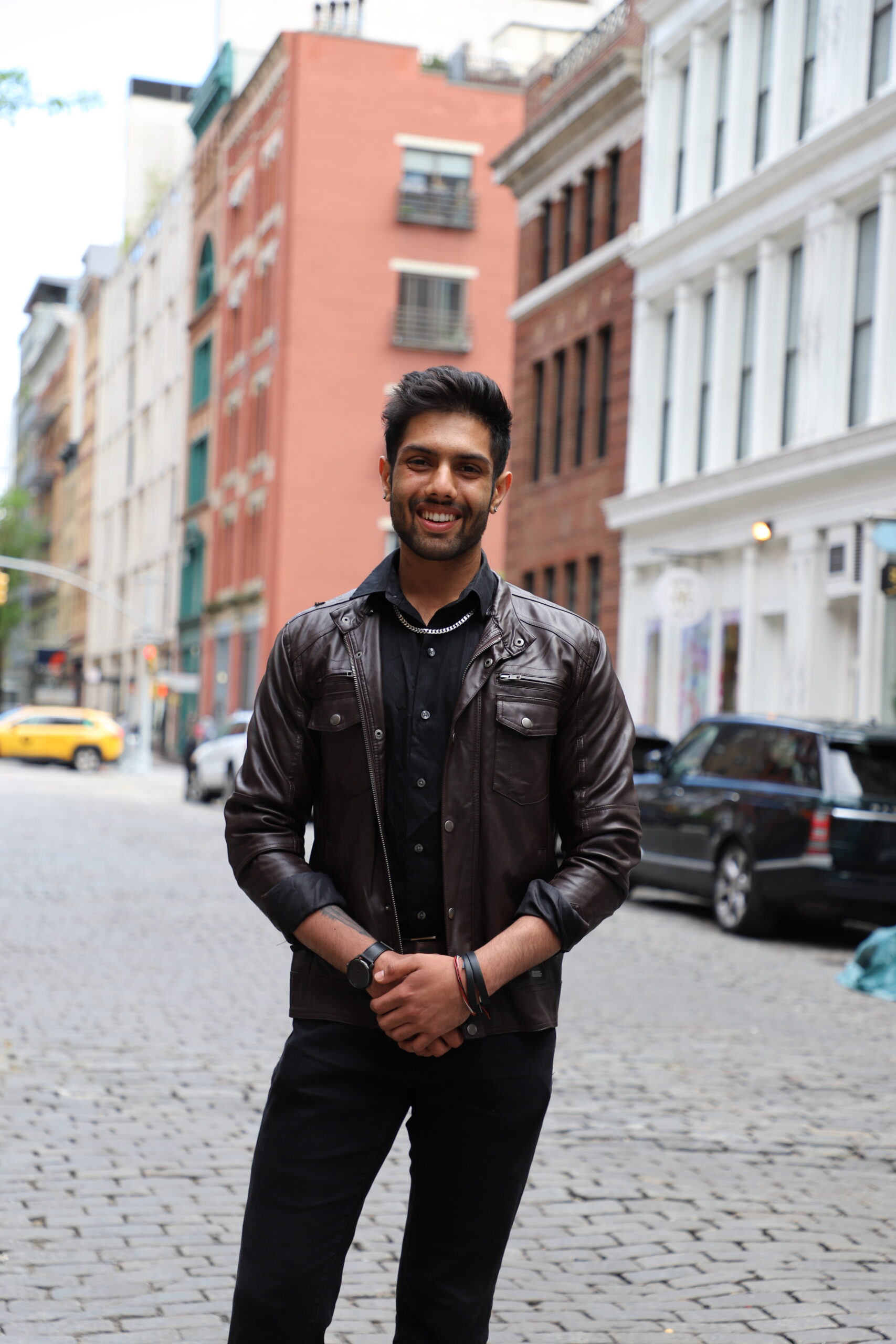 Student Dhruv Patel standing in the middle of a cobblestone street in New York City.