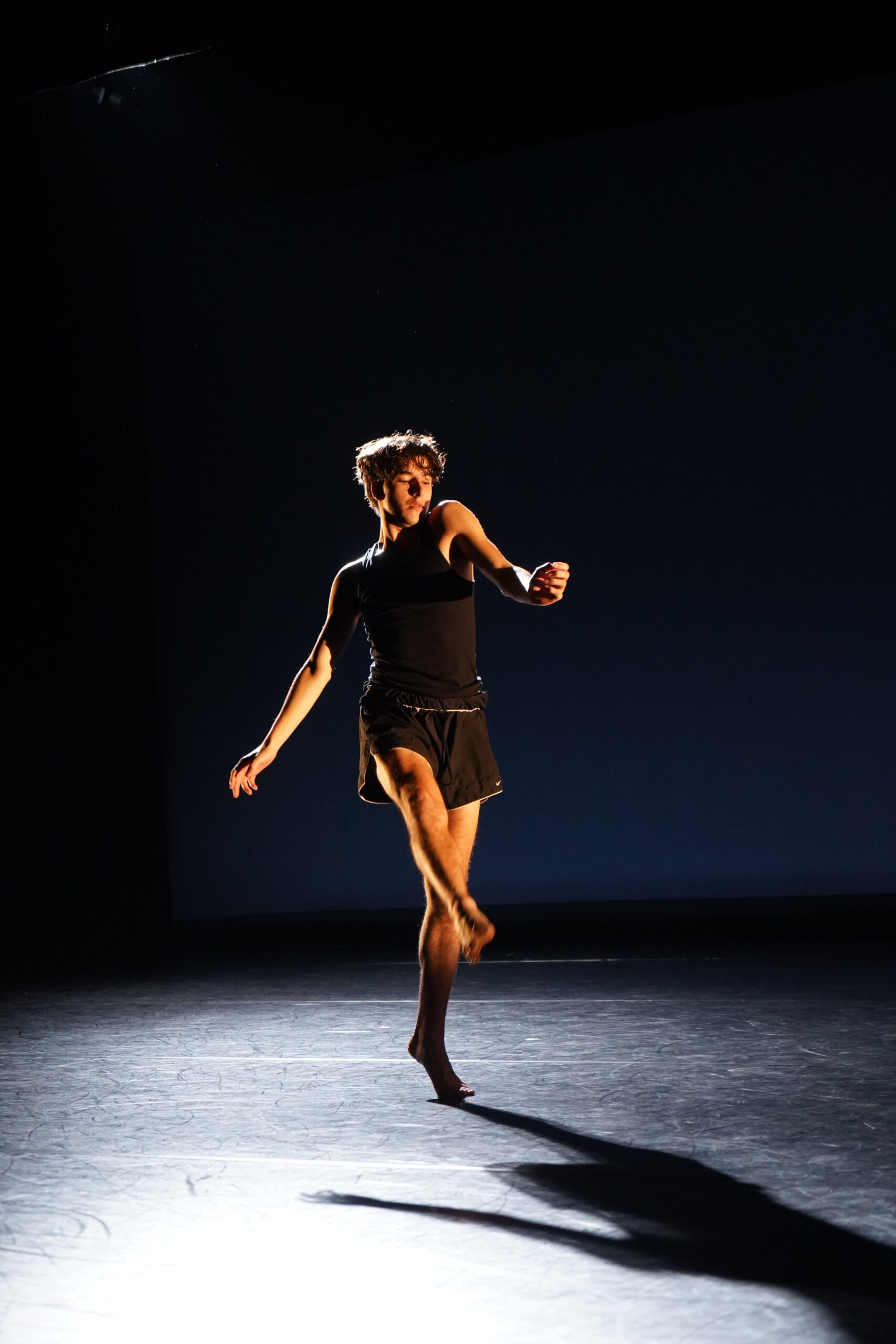 NYU Tisch Dance major Zev Haworth performing on a dimly lit stage.