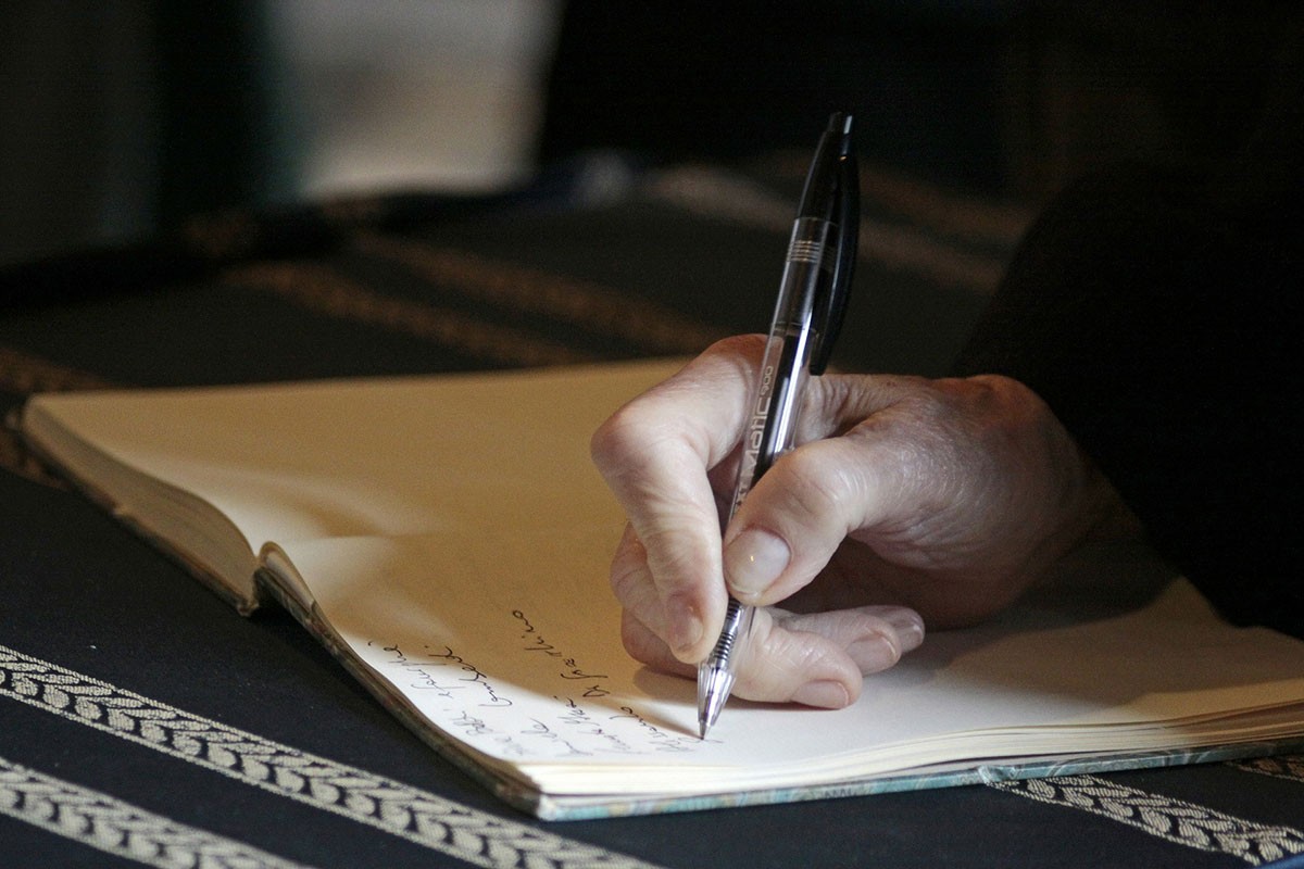 a hand writes in a notebook