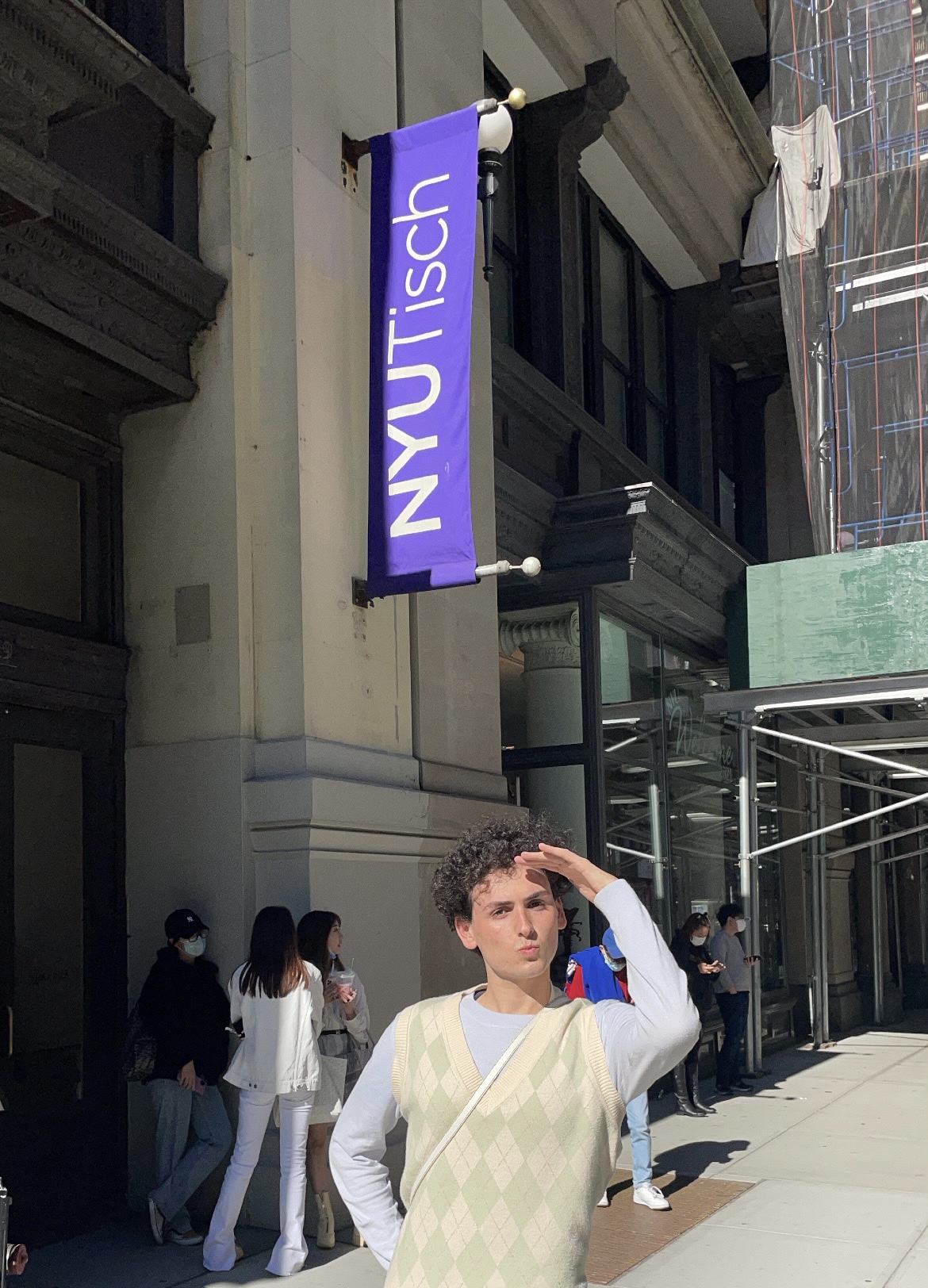 The author in front of the NYU Tisch School of the Arts building. His left hand blocks the sun from his eyes as he searches for a good place to study at NYU.