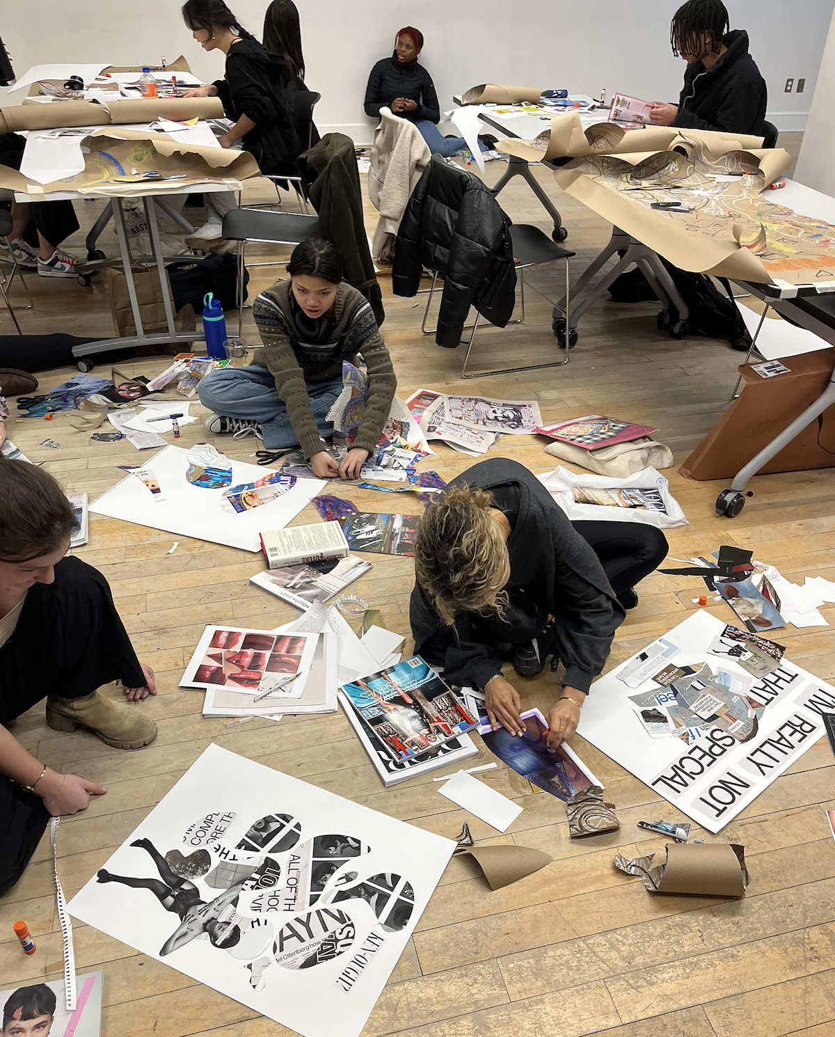 A group of students working on collage projects with cut paper