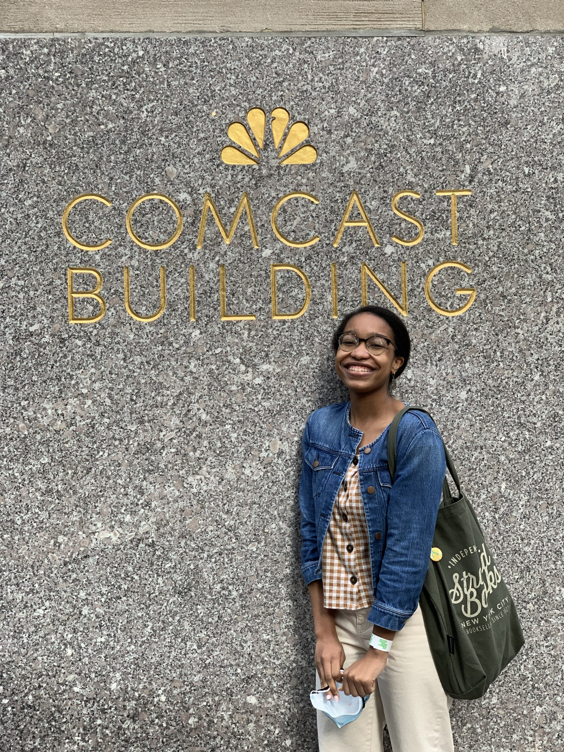 A woman of color standing in front of the Comcast Building.