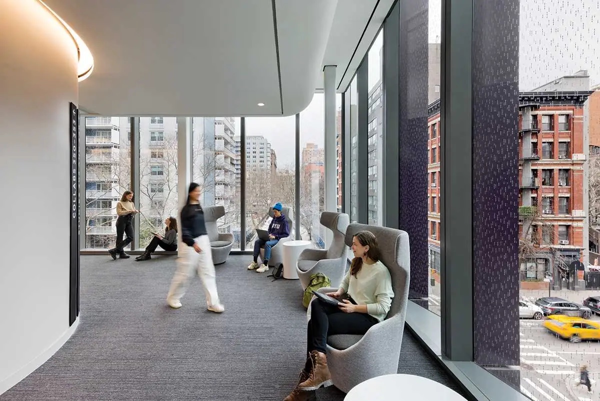 A sitting area in NYU’s John A. Paulson Center with floor-to-ceiling windows overlooking SoHo.