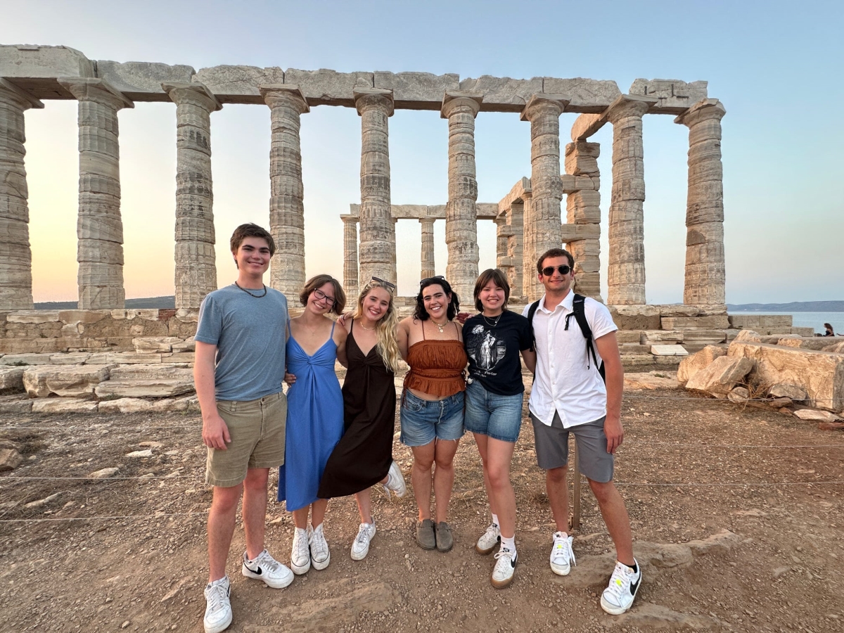 A group of six NYU students standing in front of Athenian ruins.