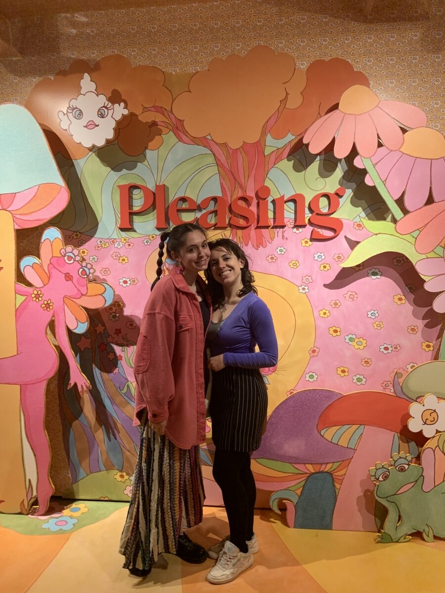 Two girls in front of a colorful wall at a pop up shop.