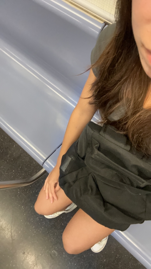 A female-presenting student traveling on the subway in New York city.