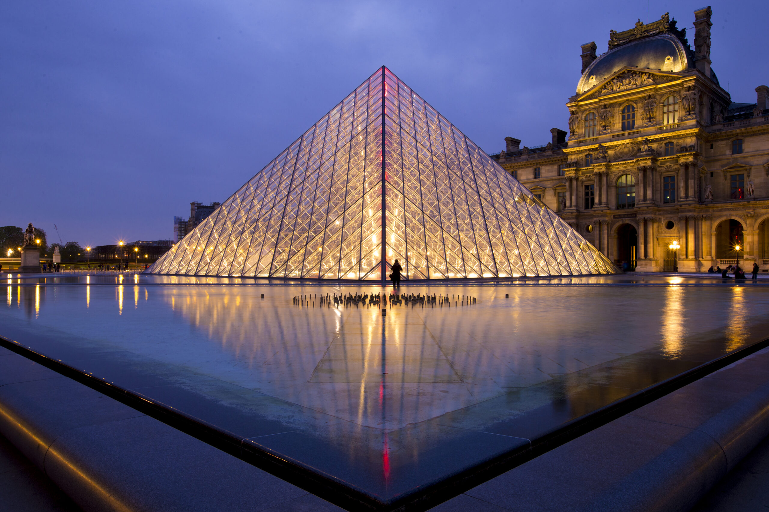 The Louvre’s glass pyramid lit up at night in Paris.