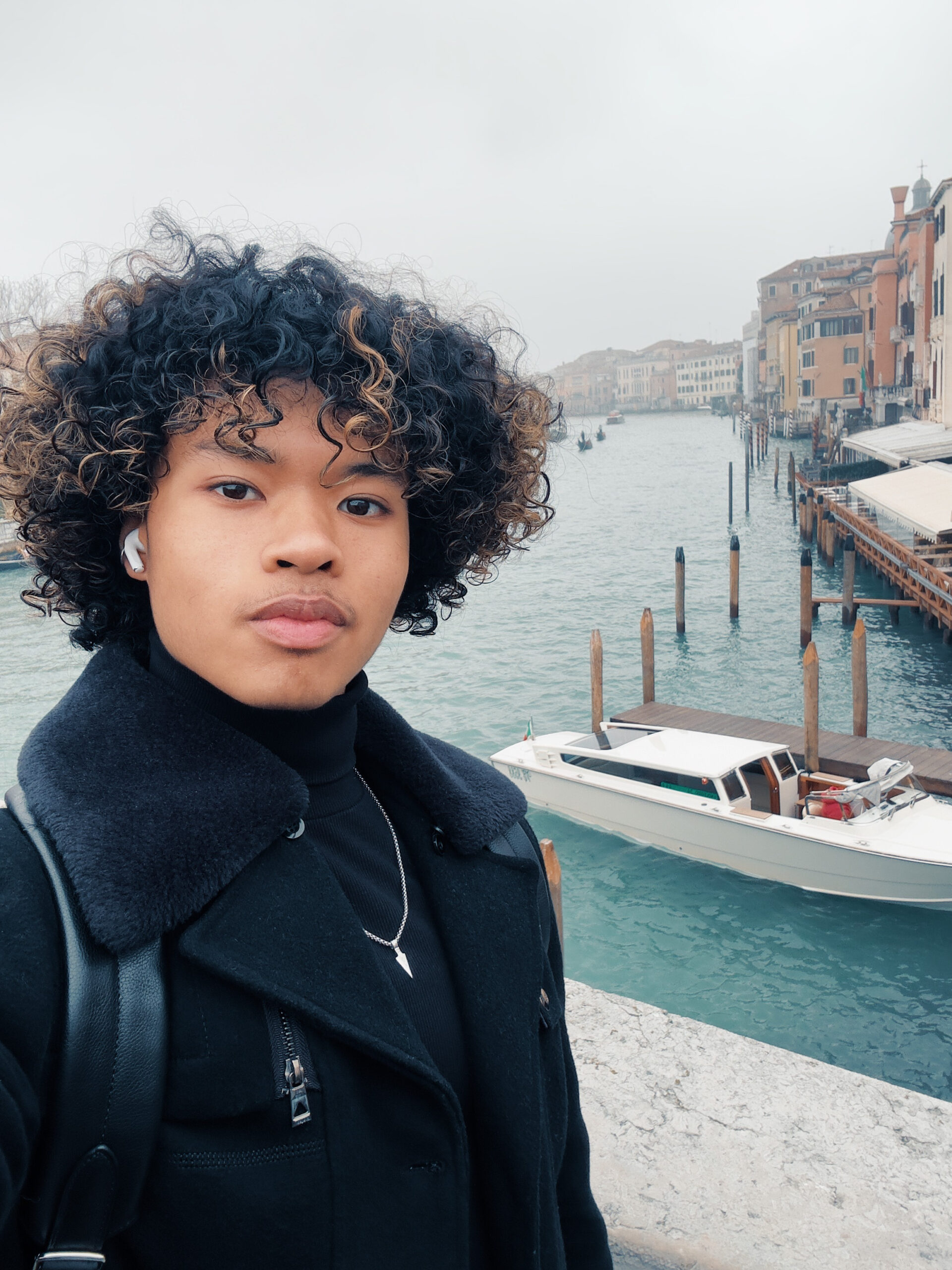 An NYU student of color standing in front of a canal in Venice.