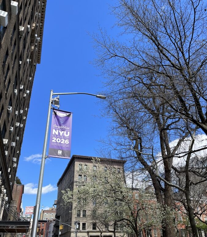 Class of 2026 banner hanging among NYU campus buildings.