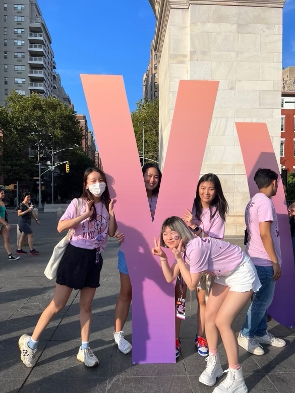 Four female-presenting NYU Welcome leaders standing in front of a life-size “Y” letter in Washington Square Park.