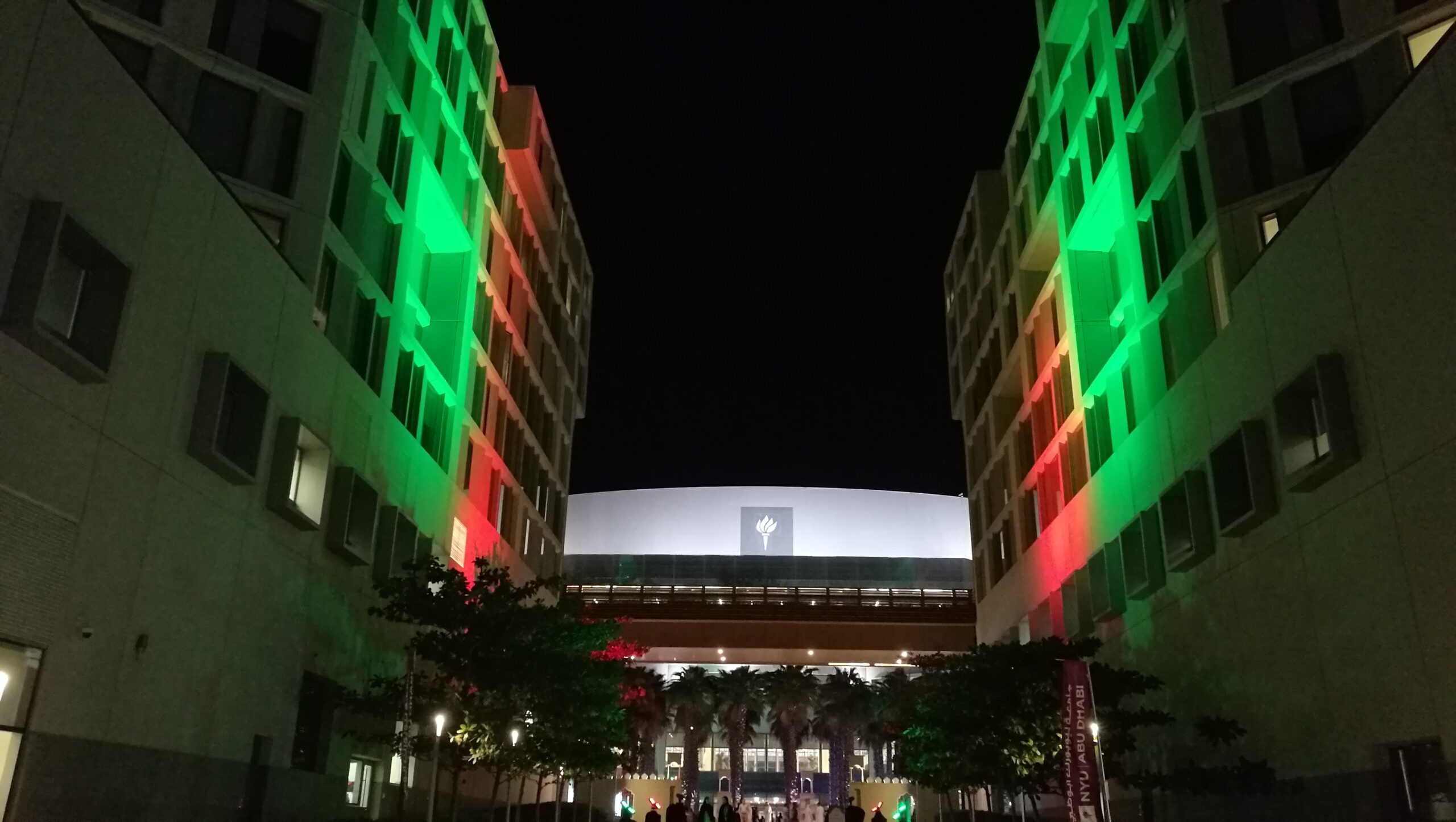 The NYU Abu Dhabi campus buildings lit up in red and green for UAE National Day.