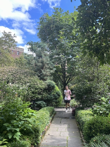 A boy walking through a verdant garden.
