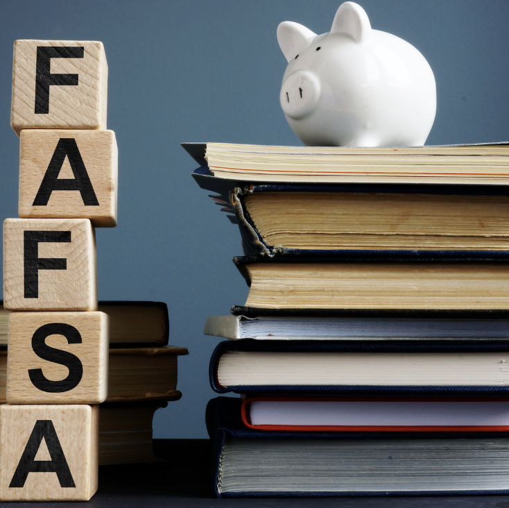 A piggy bank sits atop a stack of books and by wooden blocks that read FAFSA