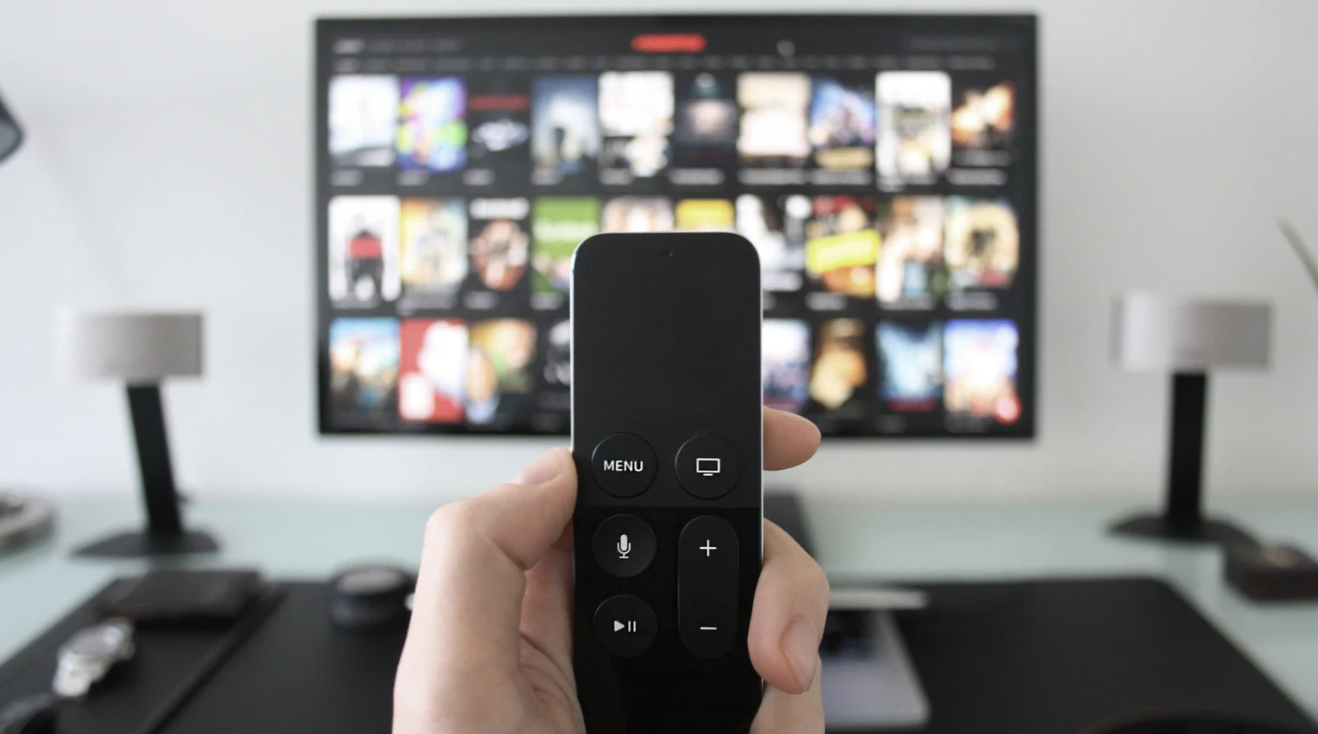 A hand holds a remote poised in front of a tv full of streaming options