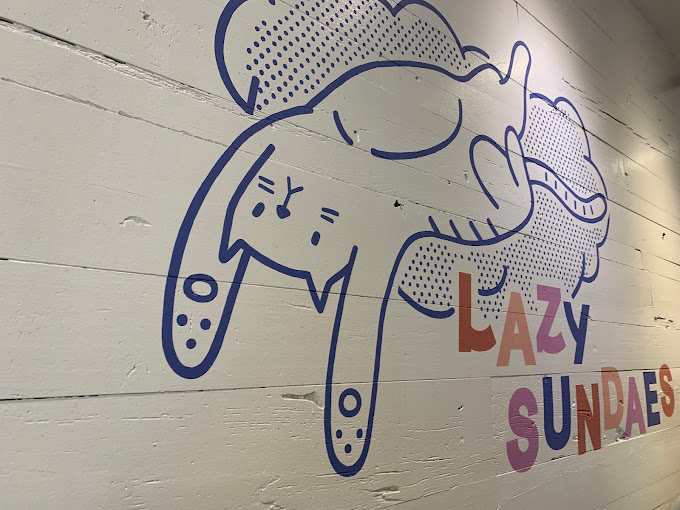 The logo of Lazy Sundaes painted on a white brick wall.