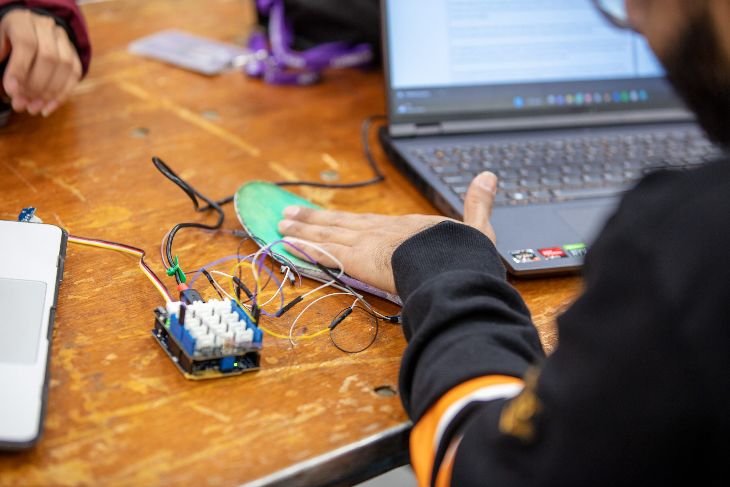 A student testing a handmade device that is connected to their laptop.