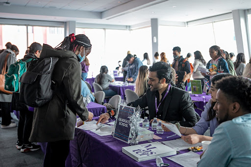 Students in front of a table booth discussing Graduate School options