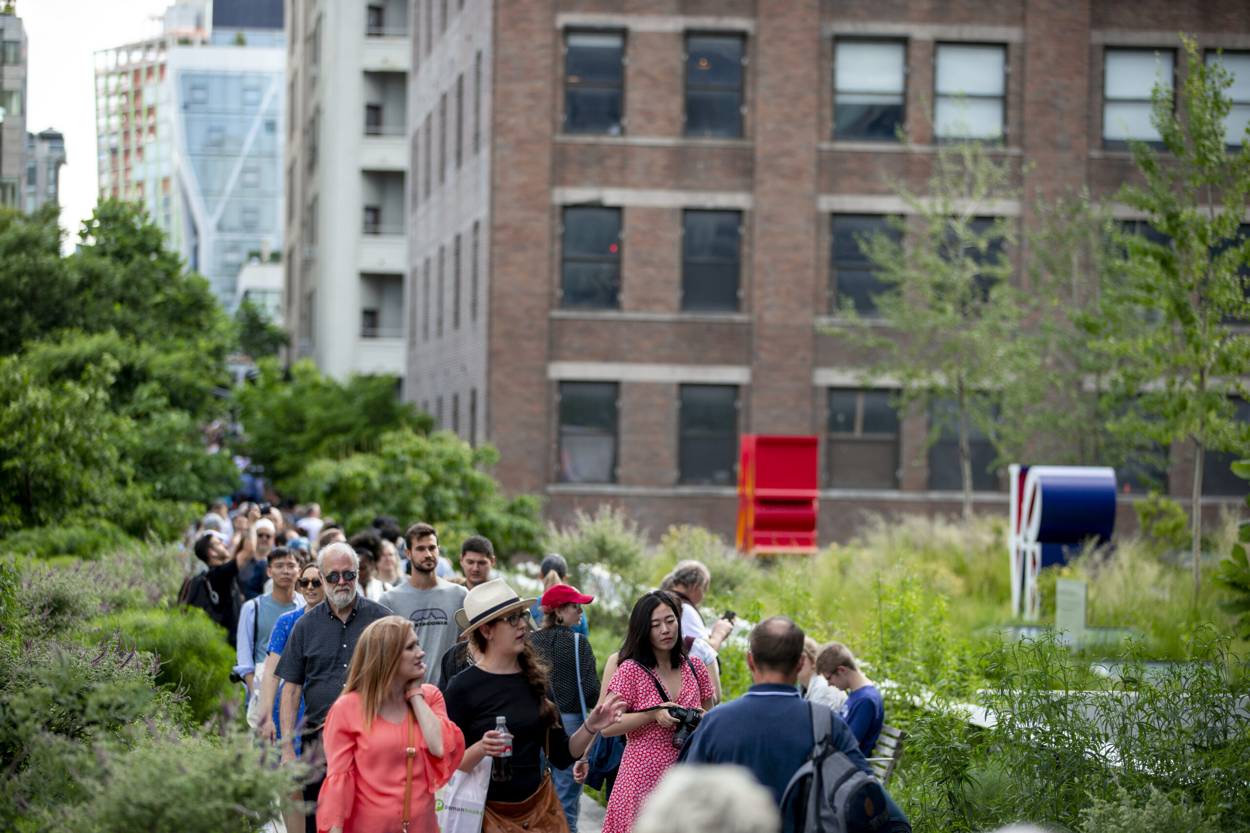 A large group of people walking along the High Line, a former railroad turned park, in New York City.