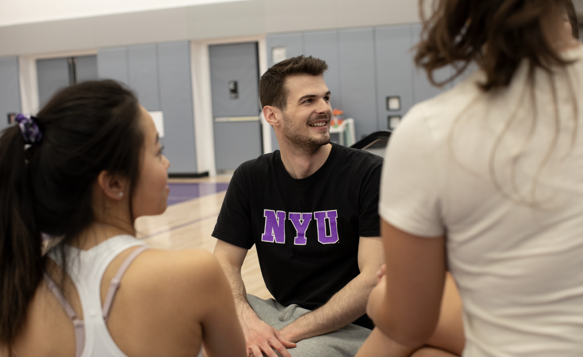 NYU students sitting in a gymnasium.