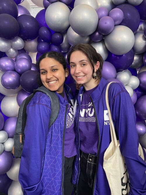 Two students in purple smiling