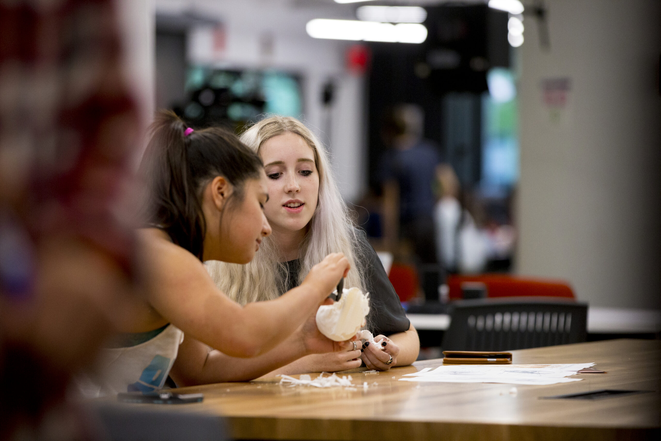 Two female-presenting students working together in the NYU Tandon MakerSpace.