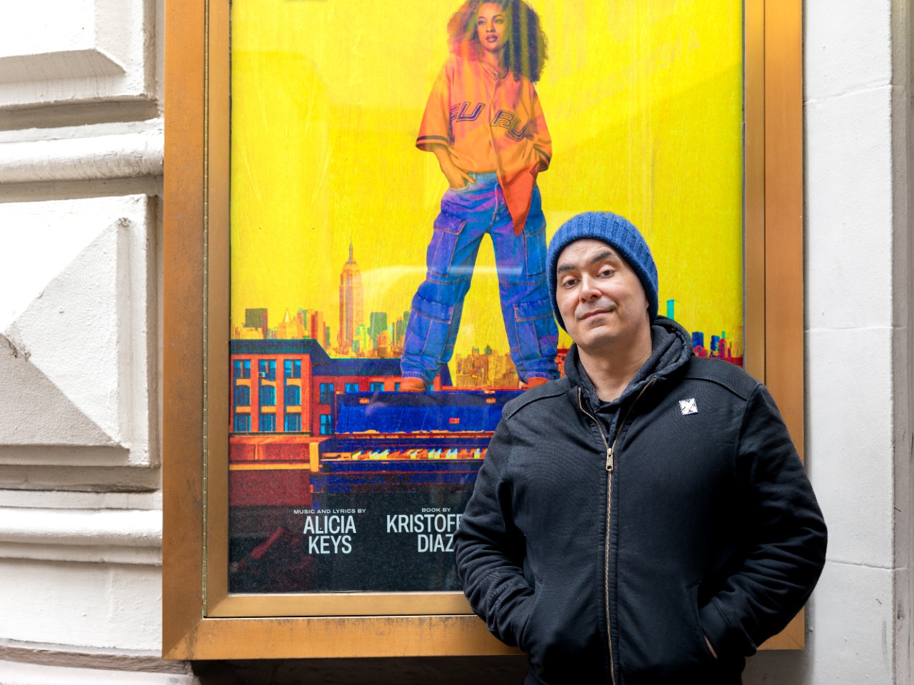 Playwright and NYU associate arts professor Kristoffer Diaz stands in front of a poster for the new musical “Hell’s Kitchen.”
