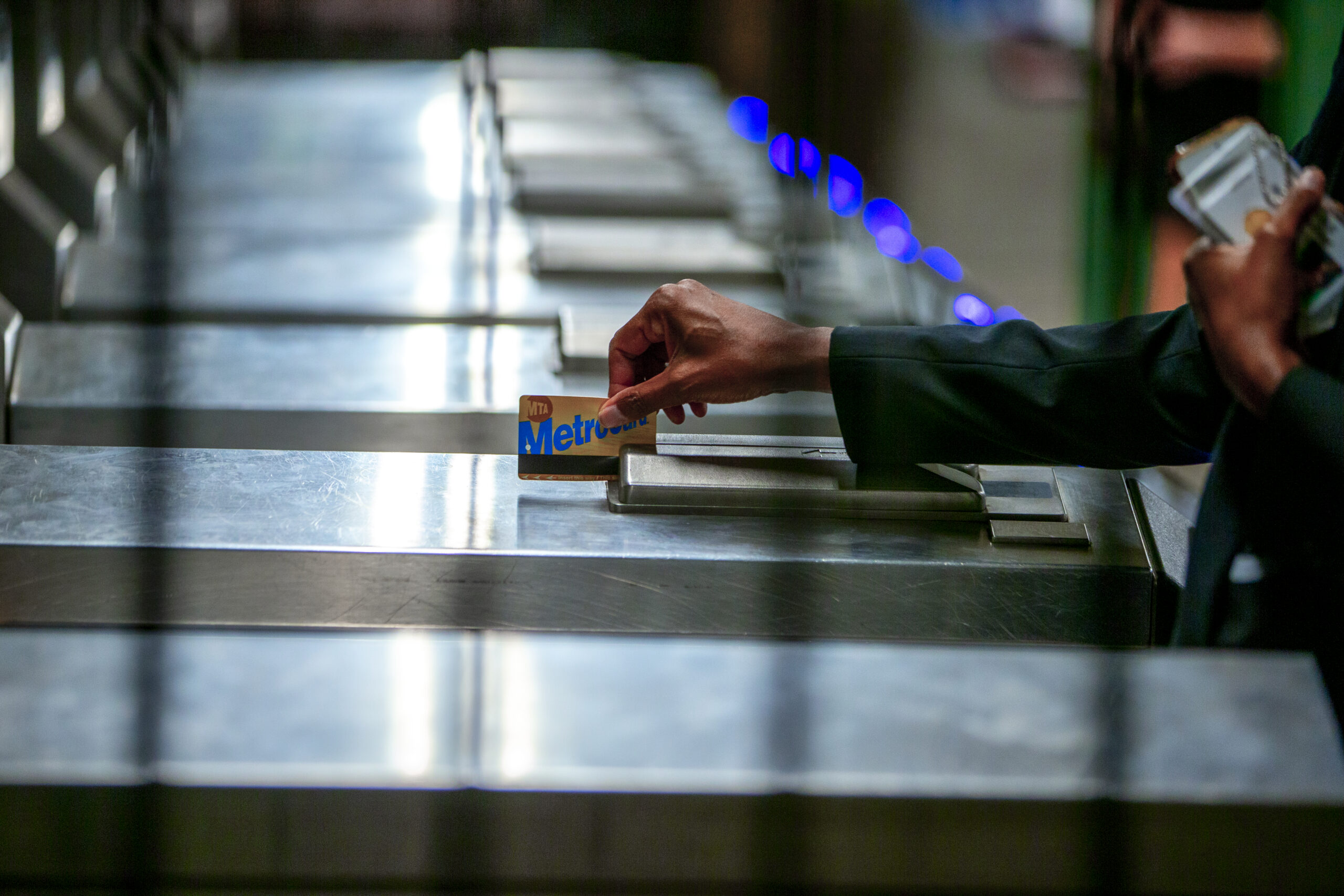 Close-up of an individual swiping their Metrocard at a turnstile.