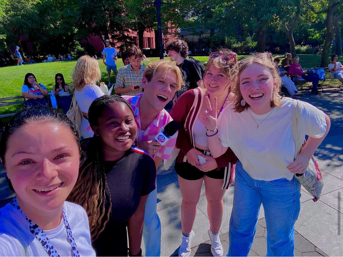 A group of friends posing for a selfie in Washington Square Park on a sunny day.