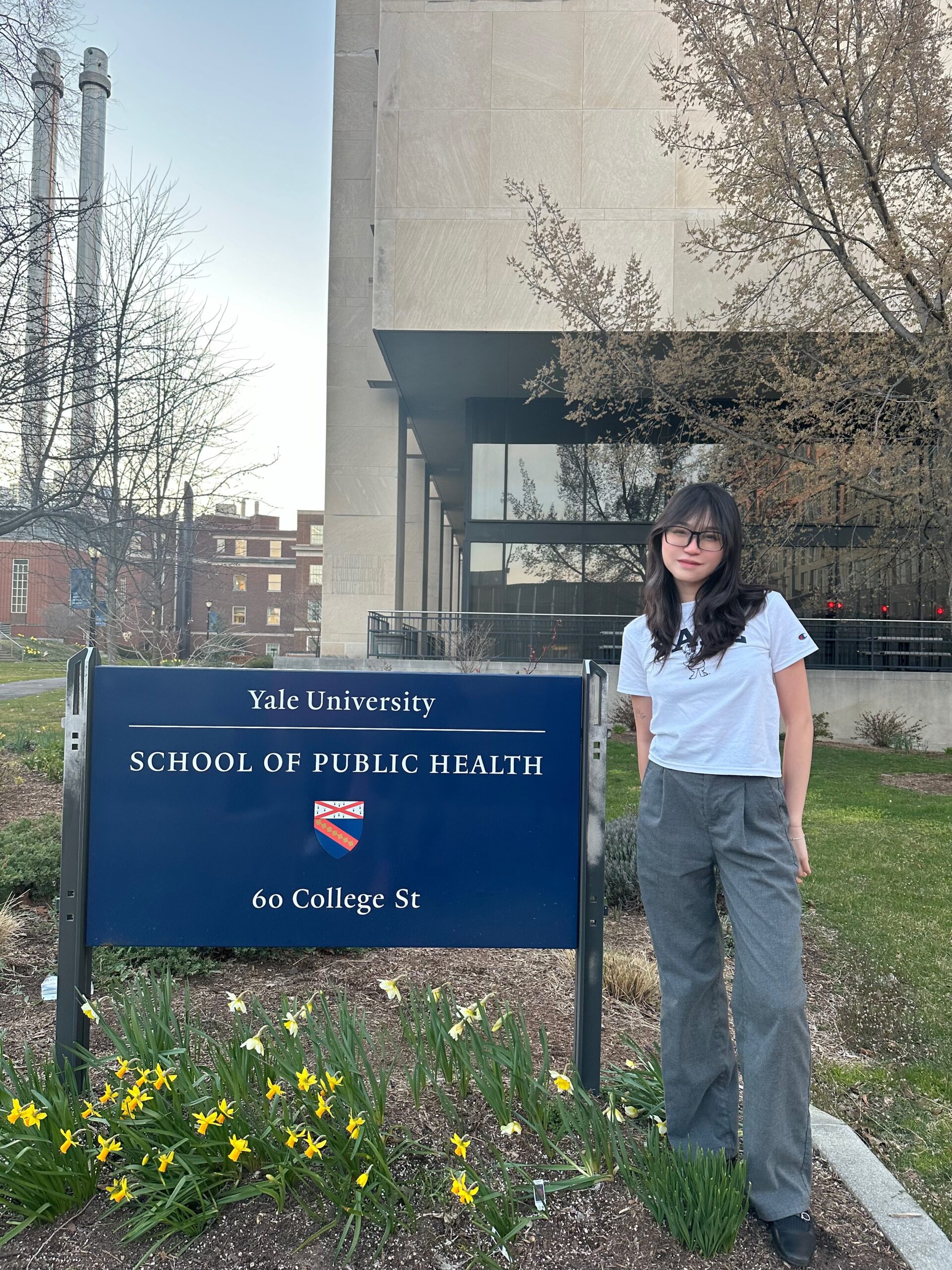 Yasmin Hung poses by the sign marking the entrance to Yale University’s School of Public Health.