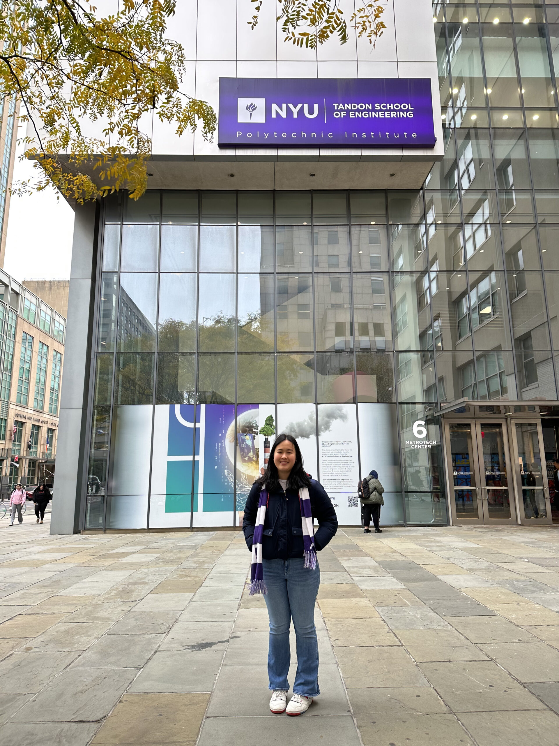 Student standing outside of a building with the NYU Tandon sign visible.